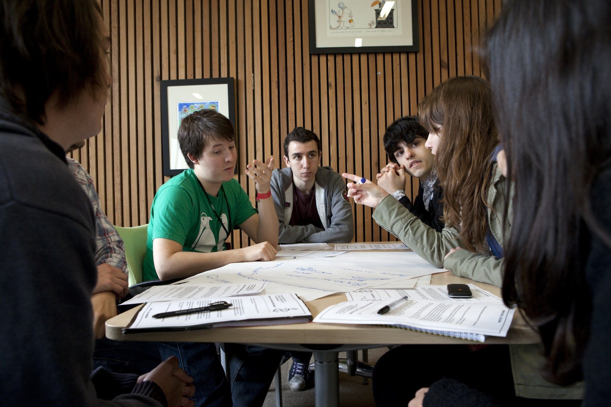 A group of young people around a table discussing ideas.