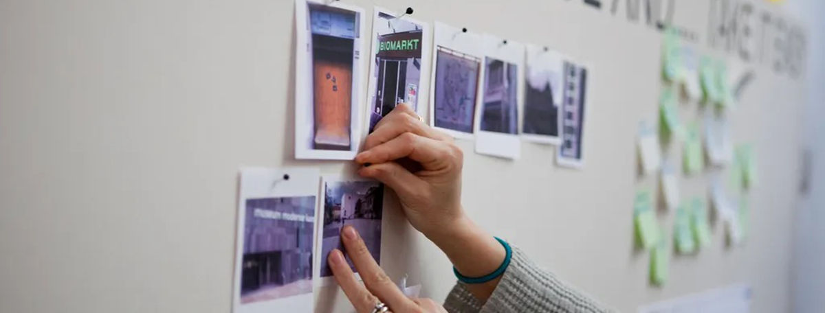 A hand placing photos on a pinboard.