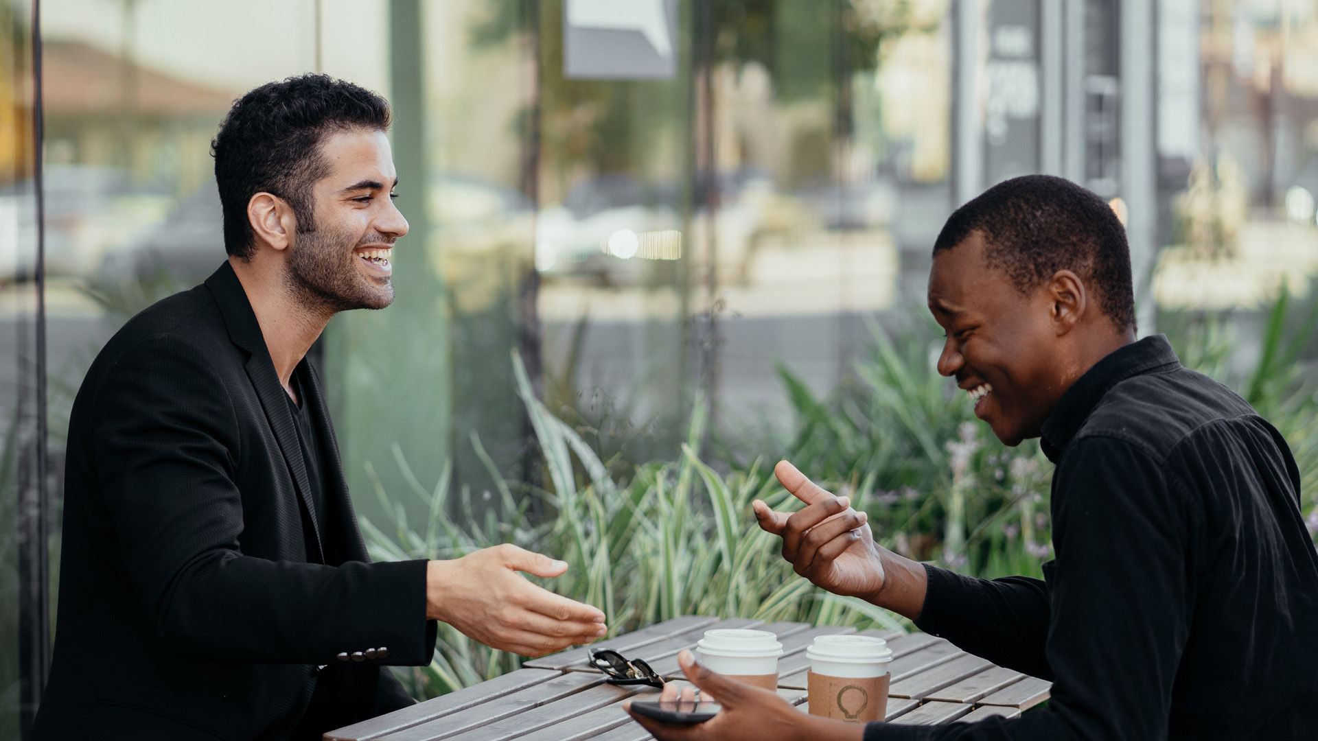 Two men having coffee outdoors at a cafe.