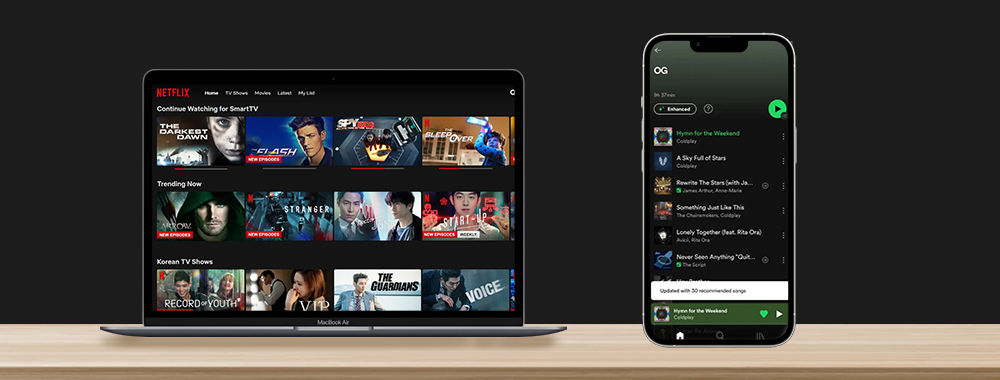 A laptop showing the personalized homescreen of Netflix on one side of the image. On the other side is a mobile phone displaying the personalized homescreen of Spotify.