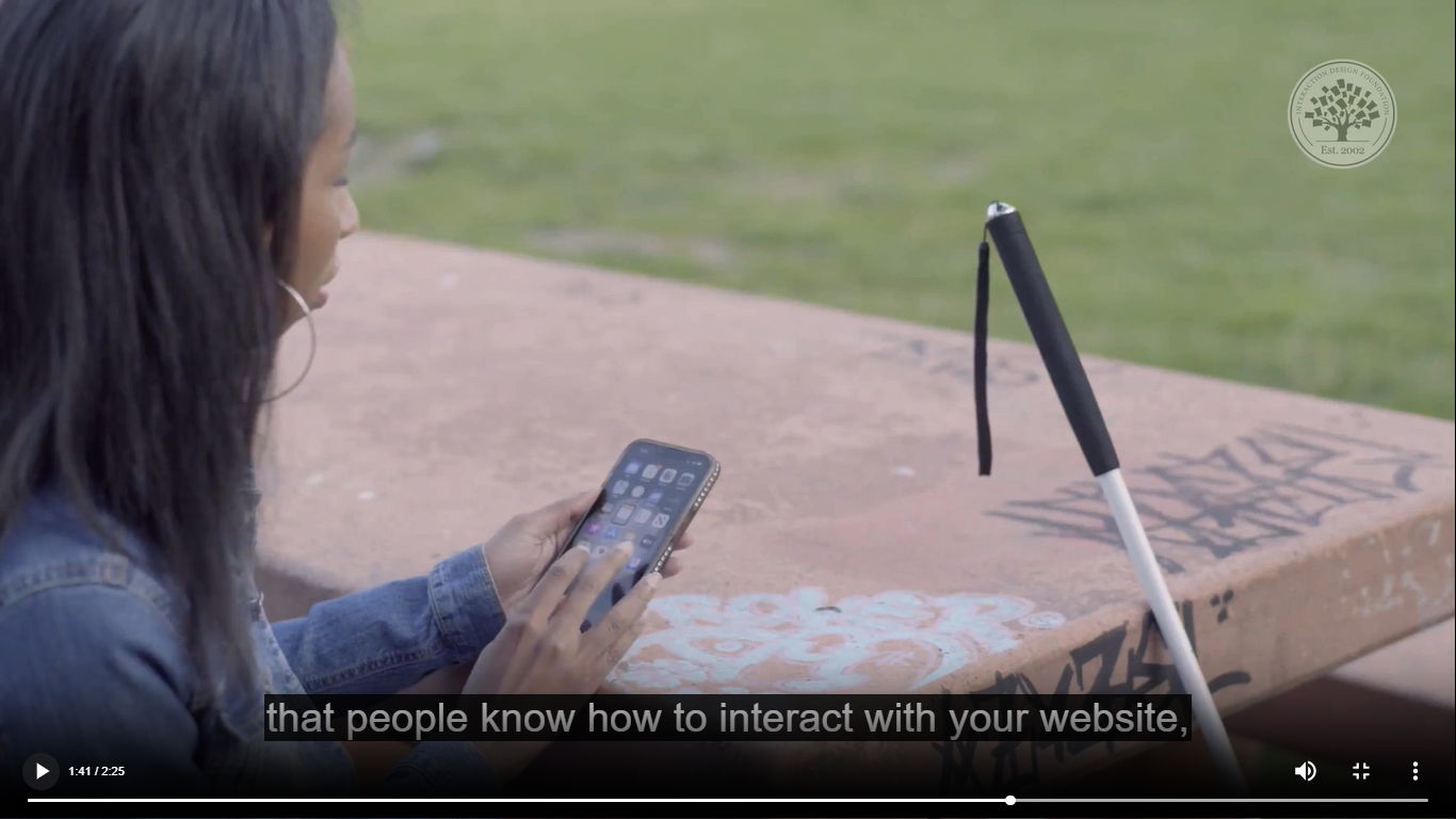 A screenshot of a captioned video showing a person using a phone.