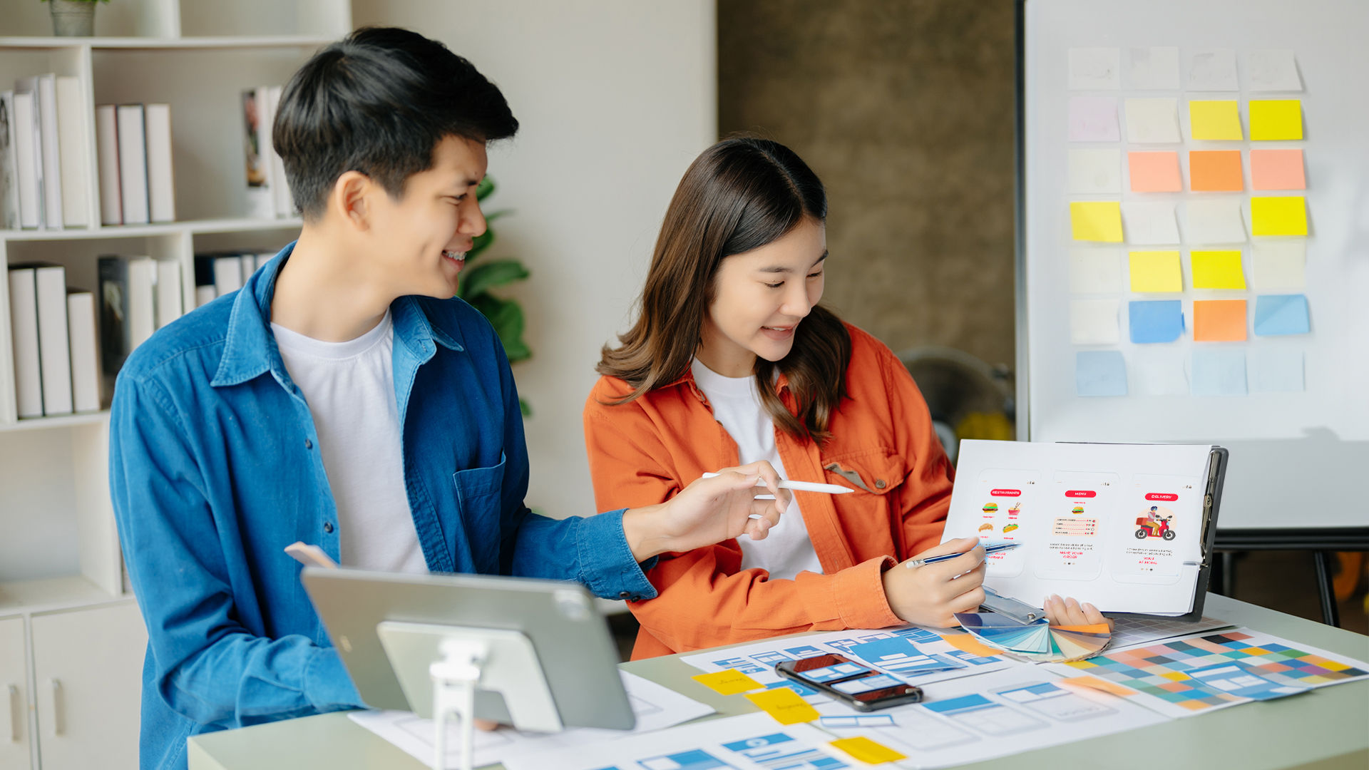 A designer and user interacting with a series of food delivery app screen mockups.