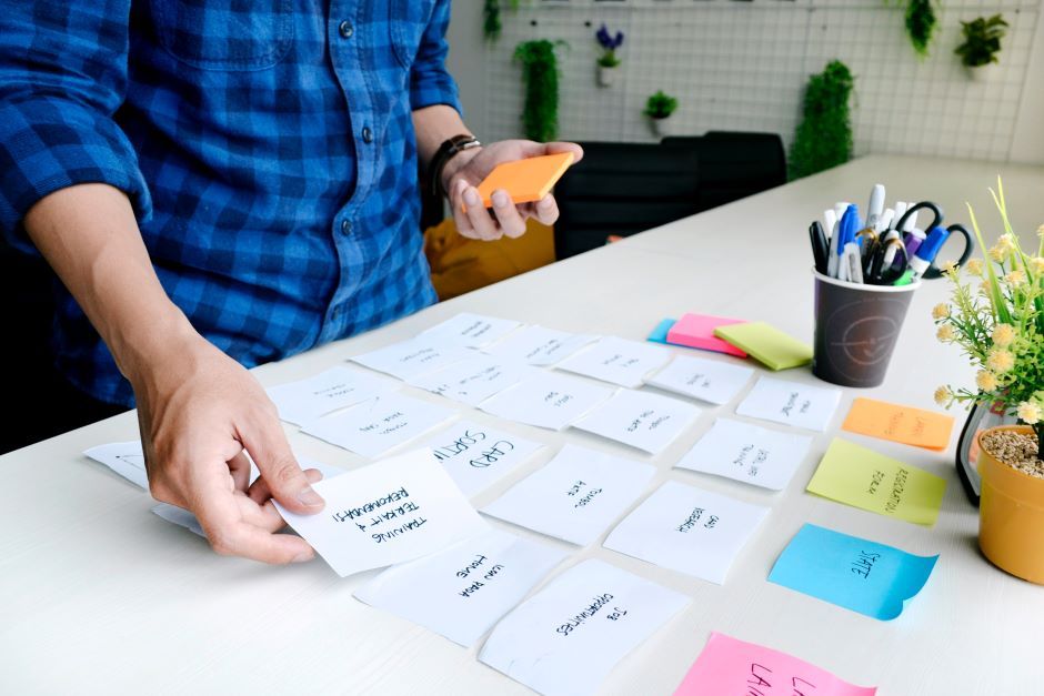 Student organizing research materials with digital and physical notes spread across a desk