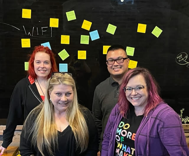 Group picture in front of board with sticky notes.